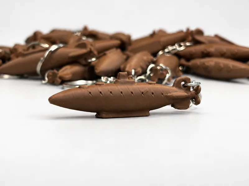 Llavero con forma de submarino impreso en 3D en PLA marrón chocolate, con el resto de la serie de 100 detrás